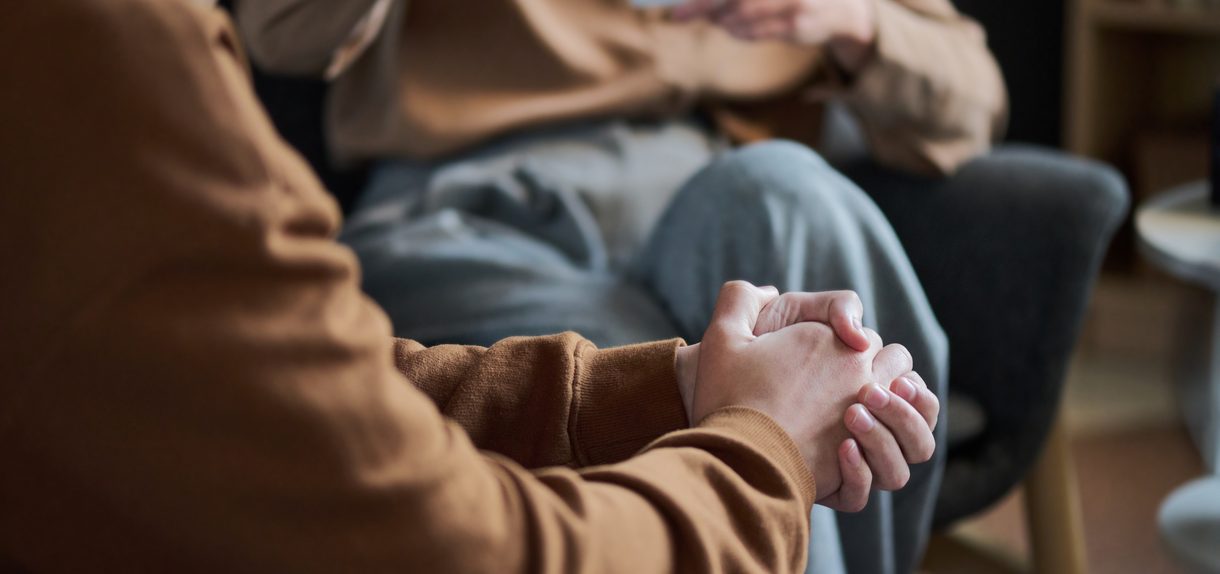 Clasped hands during an addiction therapy session